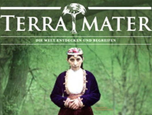 The cover of Terra Mater Magazine, a German Lead Award winner, showcases a person in traditional attire amidst a misty green forest. The magazine's title is elegantly displayed at the top in white text, adding to the serene and captivating scene.