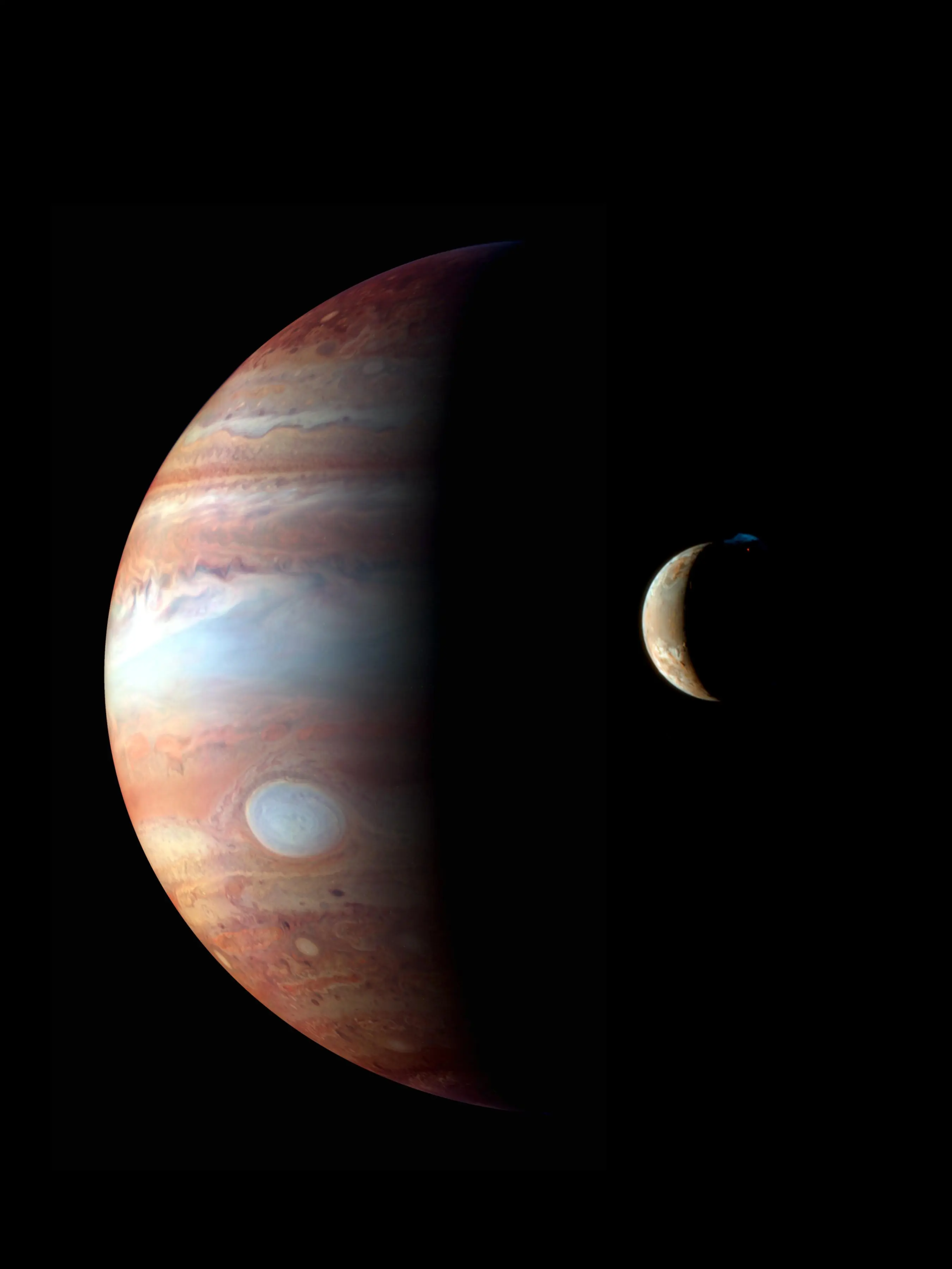 Witness the celestial drama as Jupiter reveals its majestic brown and white cloud bands, with the iconic Great Red Spot on display. In the foreground, a crescent moon, perhaps Io from this cosmic Game of Moons, is partially illuminated against the blackness of space.