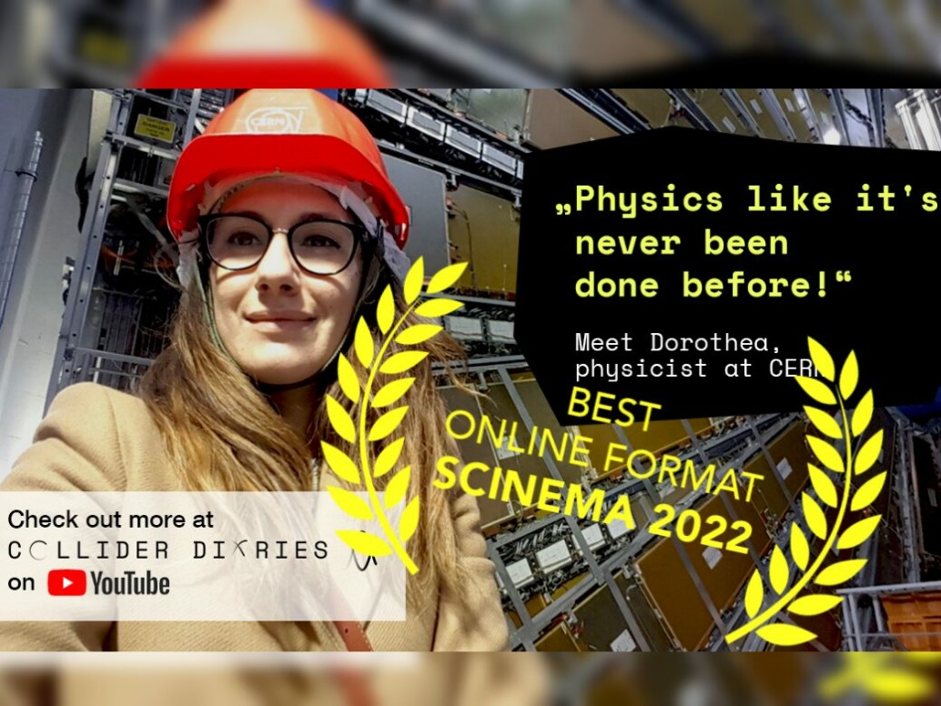 A person in a hard hat stands in front of scientific equipment. Text reads: Corporate physics like its never been done before! and BEST ONLINE FORMAT SCINEMA 2022. Check out the innovative projects on the YouTube channel, C Collider Diaries.